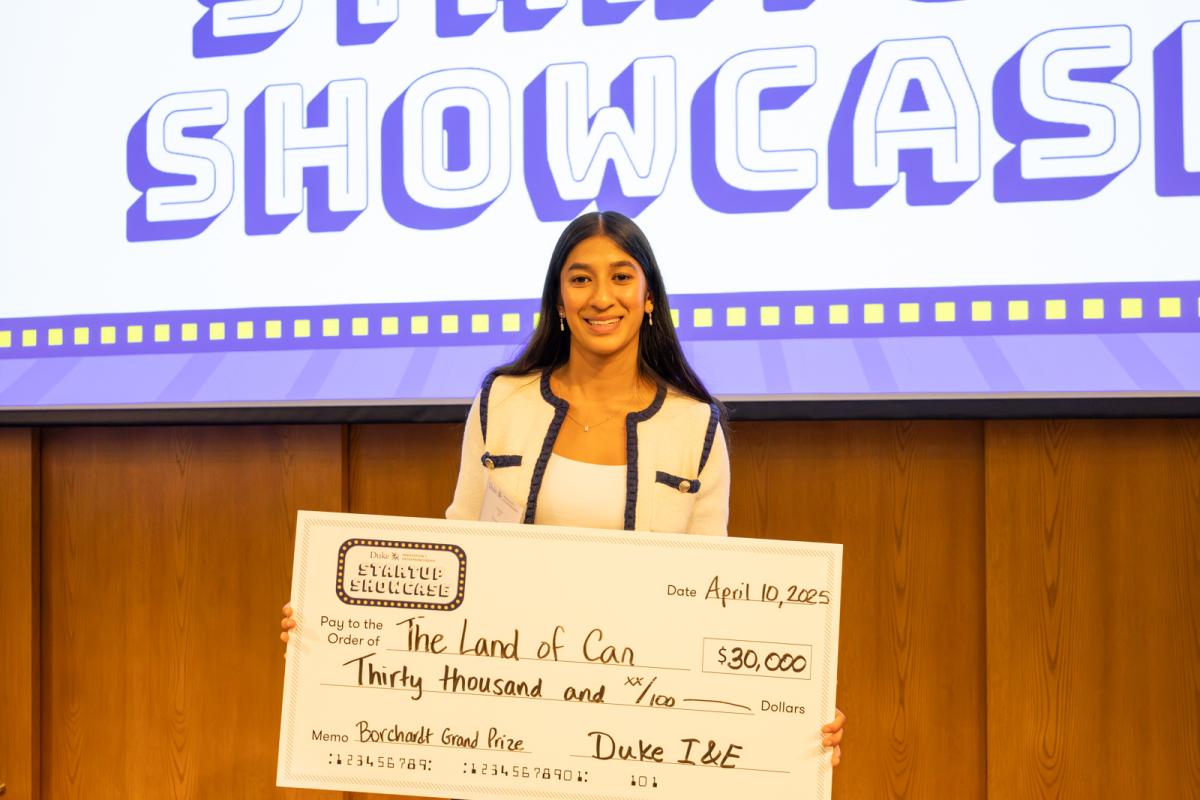 Riya Jain holds a check for Land of Can